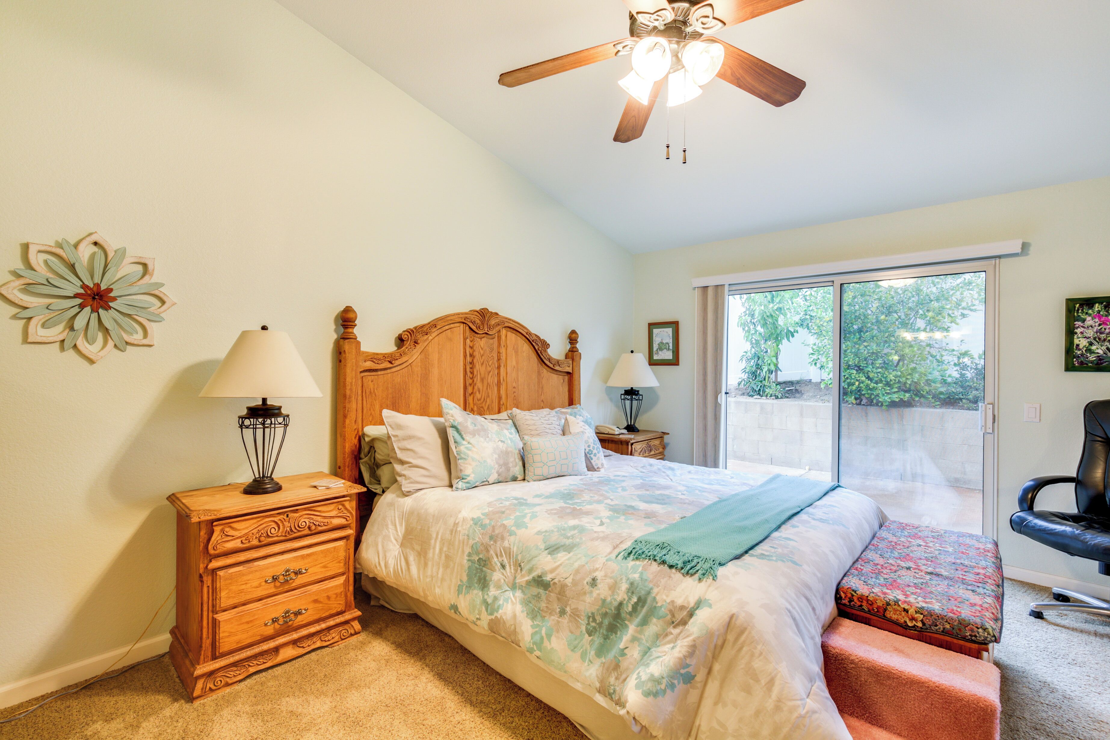 A bedroom with a bed, wooden nightstand, and a chair.