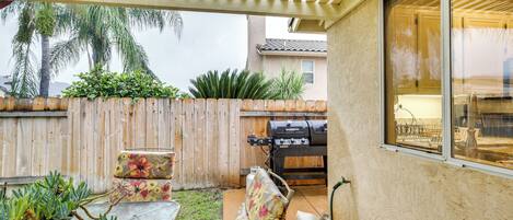 A patio area with a wooden fence, a grill, and outdoor furniture.