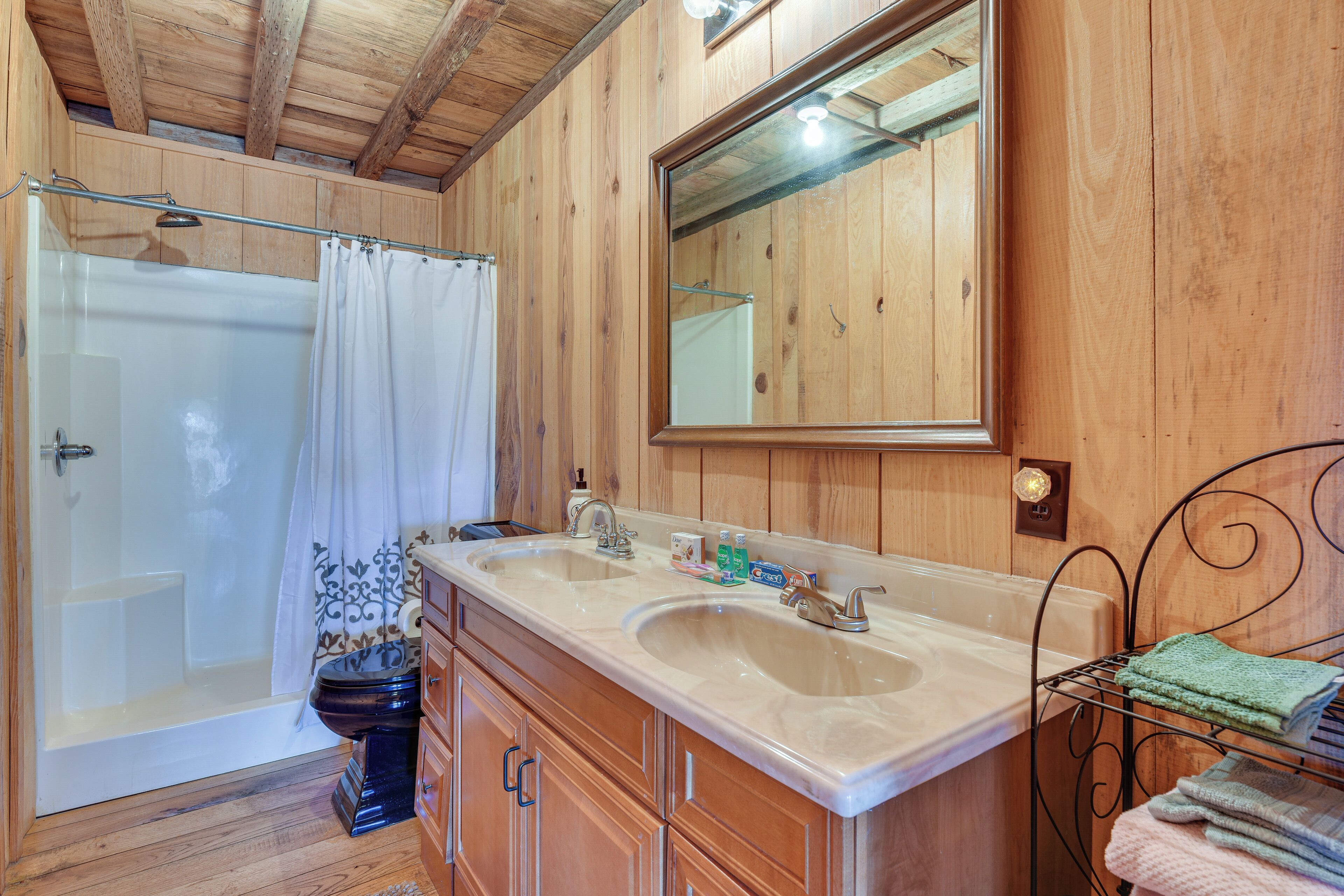 A wooden bathroom with a double sink, a bathtub, and a shower.
