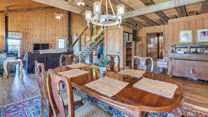 A spacious wooden dining room with a large table, chairs, and a chandelier.