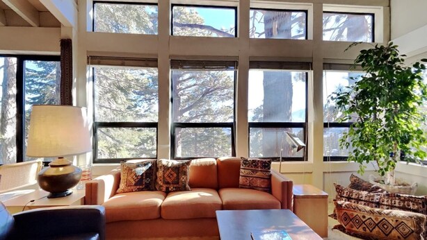 A cozy living room with a sofa, a lamp, and a large window with a view of trees. - 1849 Condos 631 4 Bedroom Home by RedAwning (Mammoth Lakes)