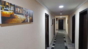 A hotel hallway with a checkered floor, a painting of a street scene, and a door with the number 204.