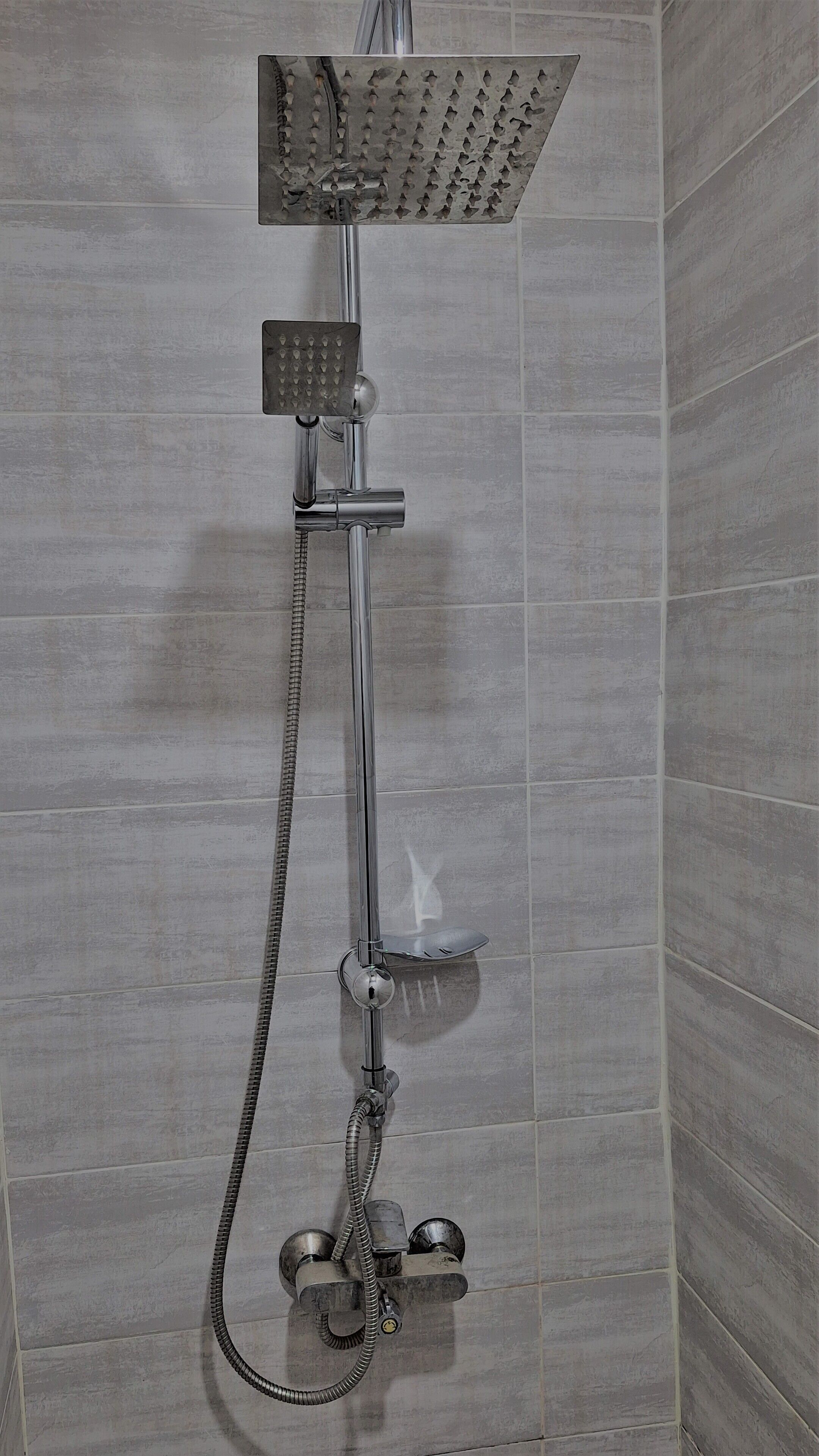 A shower with a handheld showerhead and a handheld faucet.