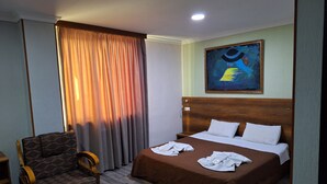 Una habitación de hotel con una cama, una silla y un cuadro en la pared.