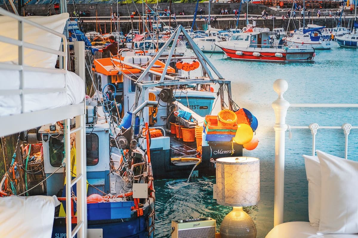 Une chambre avec un lit, une table de chevet et une vue sur les bateaux dans un port.