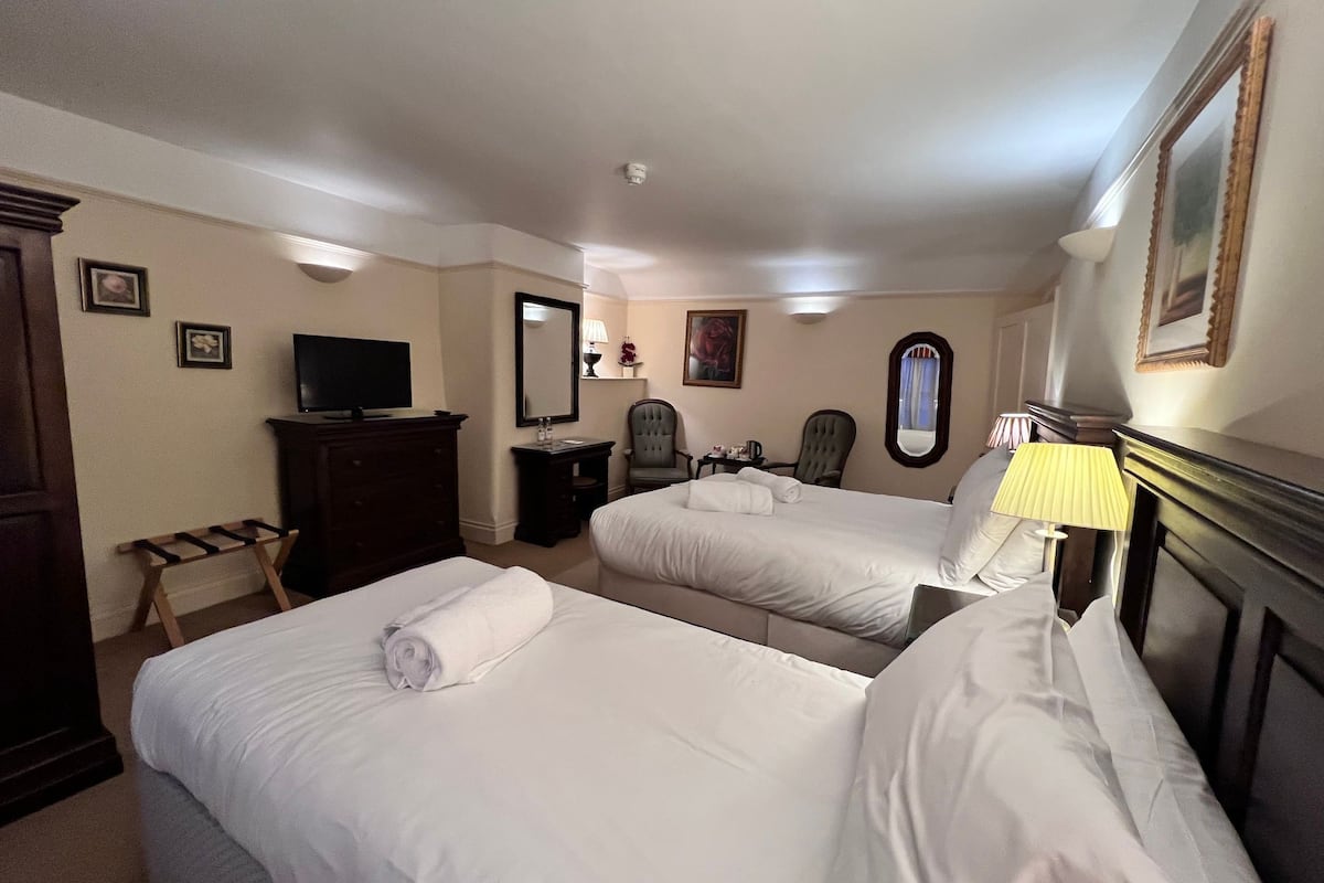 Une chambre d’hôtel avec deux lits, une télévision, un bureau et une chaise.