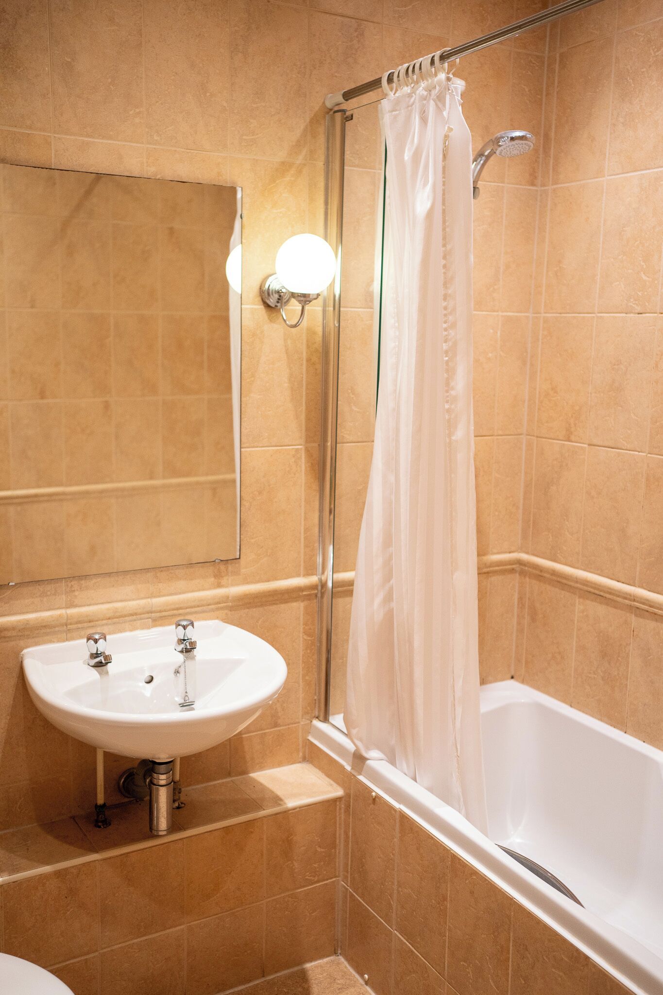 A bathroom with a sink, mirror, shower, and bathtub.