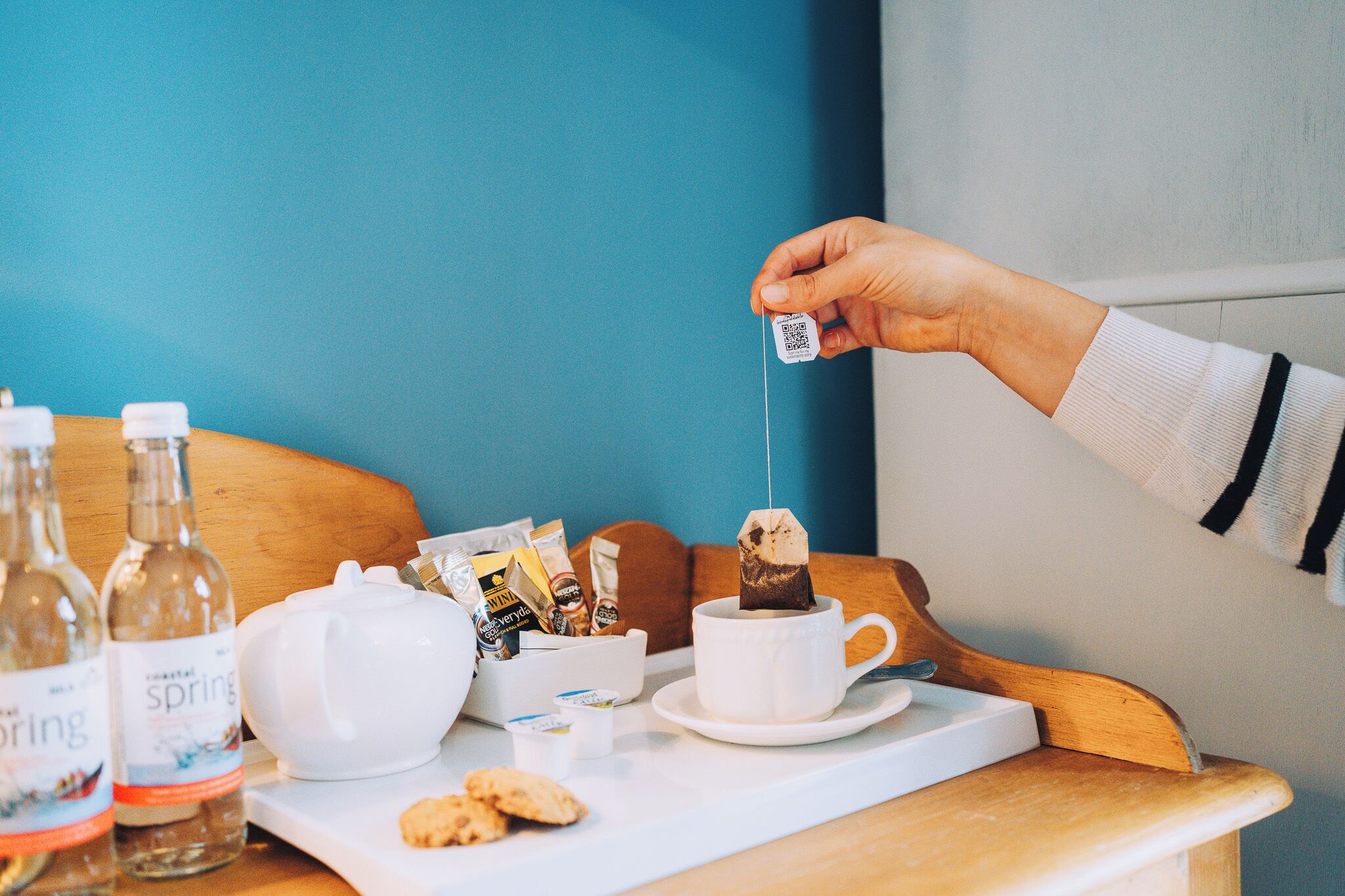 A tray with a cup of coffee, tea bags, and a teapot.