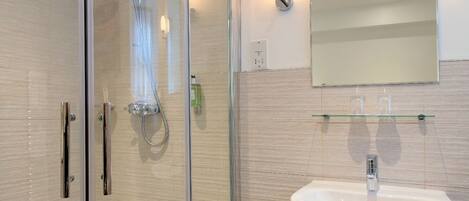 A modern bathroom with a glass-enclosed shower, a white sink, and a mirror above it.