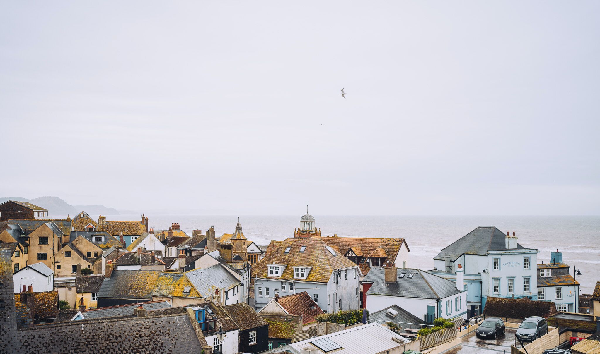 A coastal town with historic buildings, a prominent church, and a view of the sea.