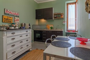 A kitchen with a white table, black cabinets, and a window with curtains.