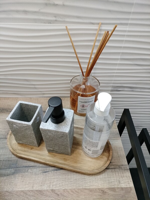 Un plateau en bois, un brûle-encens en pierre, un flacon en verre avec un couvercle noir, un flacon en verre avec un couvercle blanc et des diffuseurs à bâtonnets.
