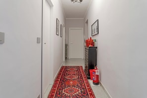 A hallway with a patterned rug, a fire extinguisher, and a radiator. - APARTMENT 15 (torino)