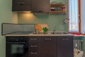 A compact kitchen with a built-in oven, a sink, and a window with a view. - APARTMENT 15 (torino)
