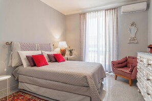 Una camera da letto con un letto, una sedia, una cassettiera e una finestra con tende.