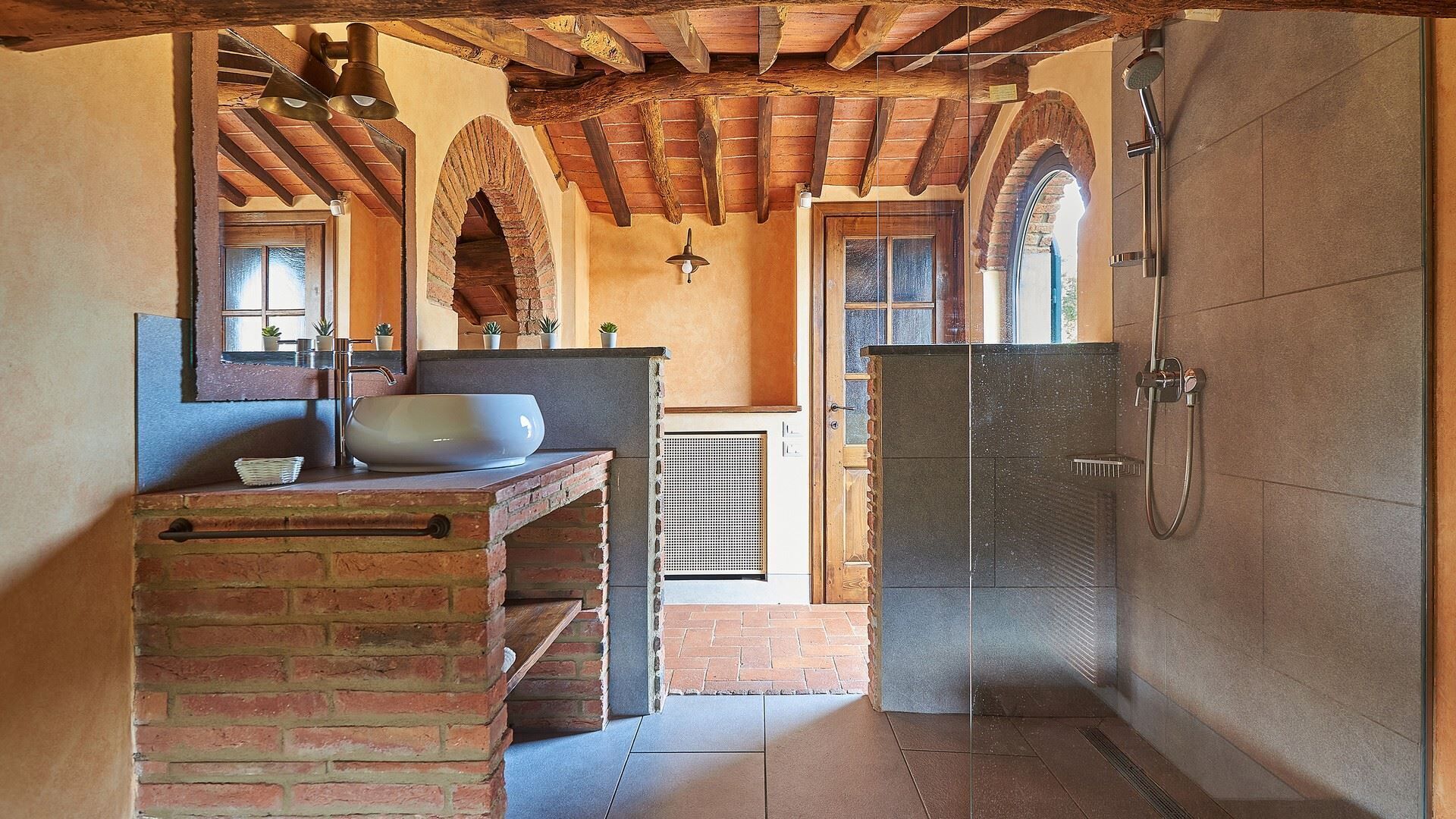 Une salle de bain rustique avec un lavabo en briques, un grand miroir et un espace douche.