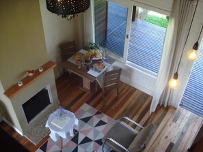 A dining area with a wooden table set for four, a fireplace, and a view of the outdoors through large windows. - Pousada Toscana Cambará (Cambara do Sul)