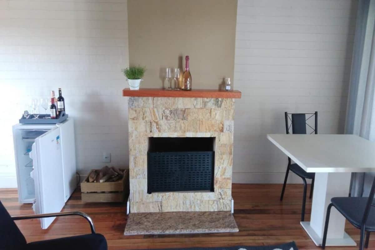 Um quarto com lareira de pedra, uma mesa de jantar e uma pequena cozinha.