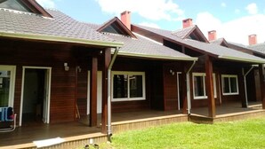 A row of wooden cabins with pitched roofs and chimneys, each with a porch and large windows. - Pousada Toscana Cambará (Cambara do Sul)