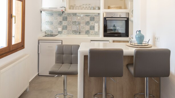 A modern kitchen with a central island, bar stools, and pendant lighting.