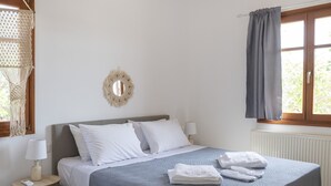 A neatly arranged bedroom with a bed, bedside table, lamp, and a hanging light fixture.
