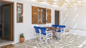 An outdoor patio with a stone floor, wooden furniture, and a pergola providing shade.