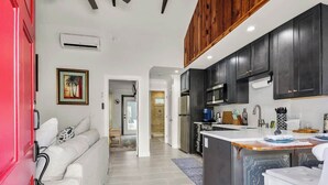 A modern kitchen with dark cabinets, a central island, and a red door.