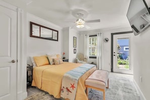 A bedroom with a bed, bedside table, chair, ceiling fan, and a door leading to a balcony. - Historic 1bed 1bath Suite Steps to River St! (Savannah)