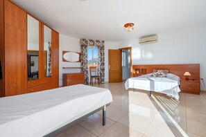 A bedroom with a bed, a wardrobe, a chair, a desk, and a window with curtains.