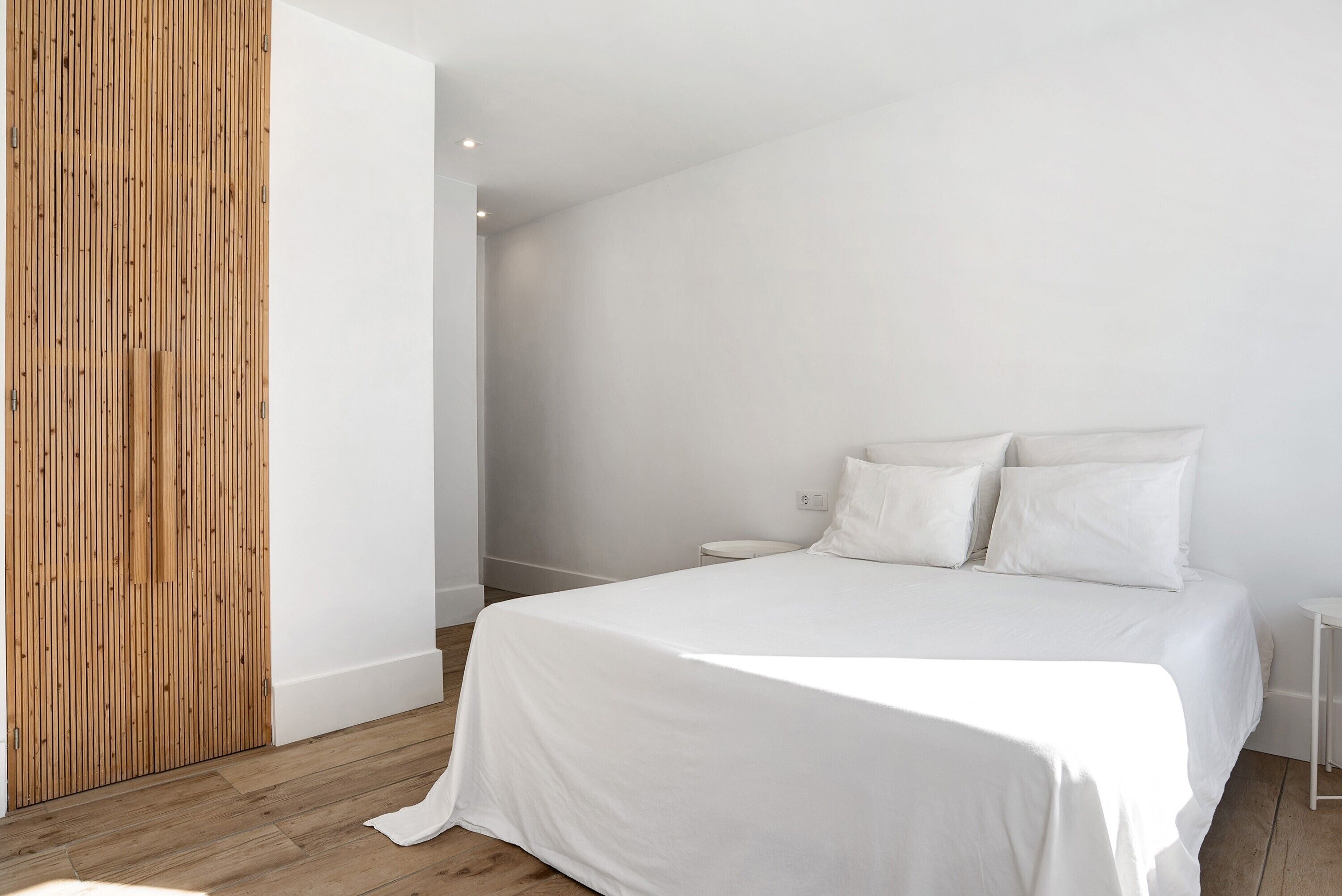 Un dormitorio con una cama grande, un panel de madera en la pared y suelo blanco.
