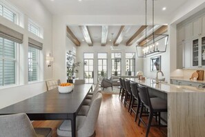Un comedor amplio con una mesa larga, varias sillas y una zona de cocina con encimera de mármol.