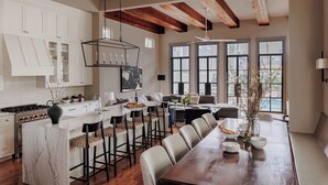 Una cocina amplia con armarios blancos, una isla grande y un comedor con una larga mesa de madera.