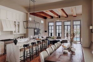 A spacious kitchen with white cabinets, a large island, and a dining area with a long wooden table.
