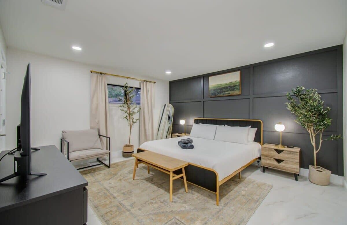 With a beautiful accent wall as well as a sitting area, TV, greenery, and full-length mirror, this bedroom offers all the comforts of home and more!