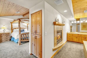 A bedroom with a four-poster bed, wooden wardrobe, and a fireplace.