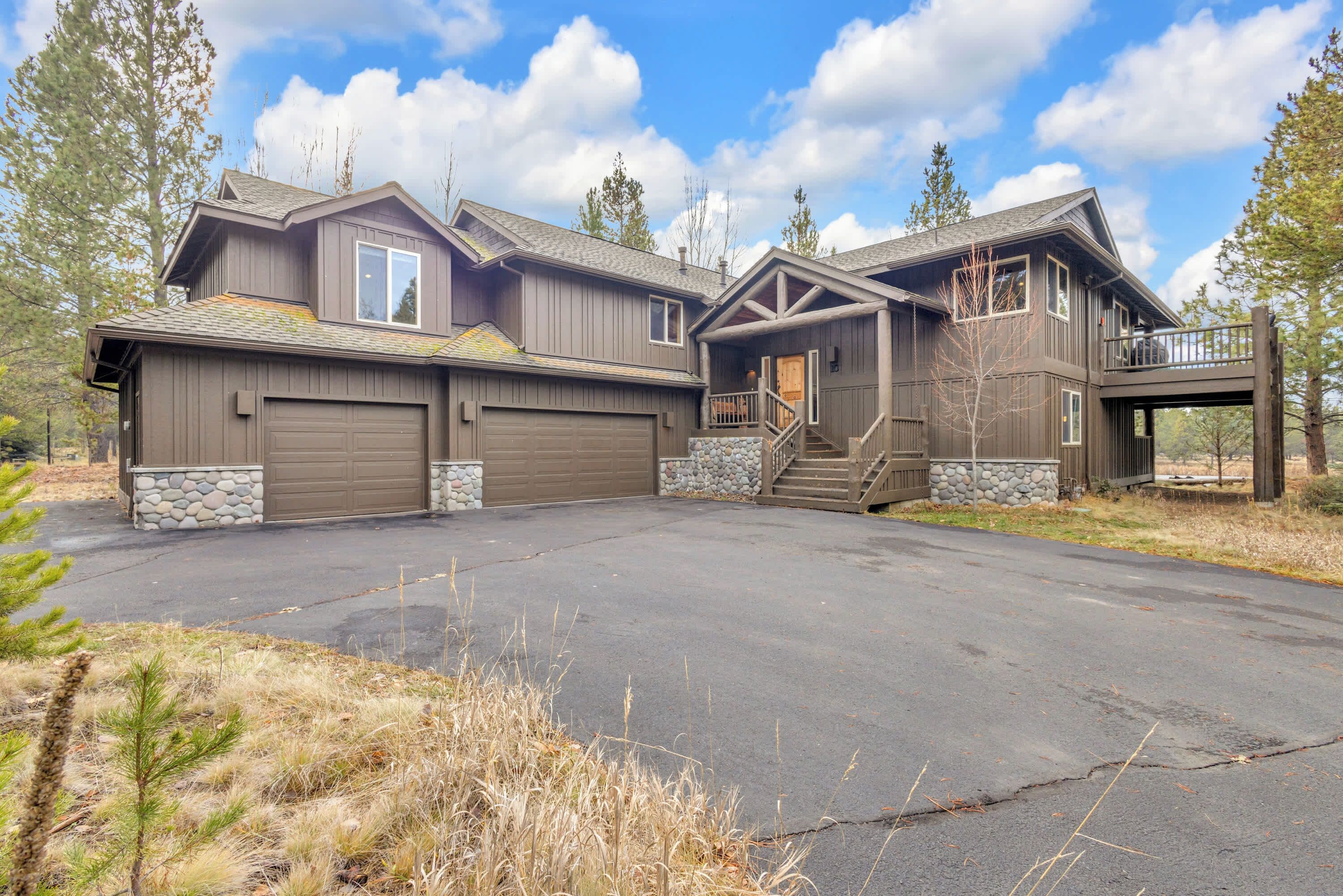 A two-story house with a stone foundation, a covered front porch, and a garage.