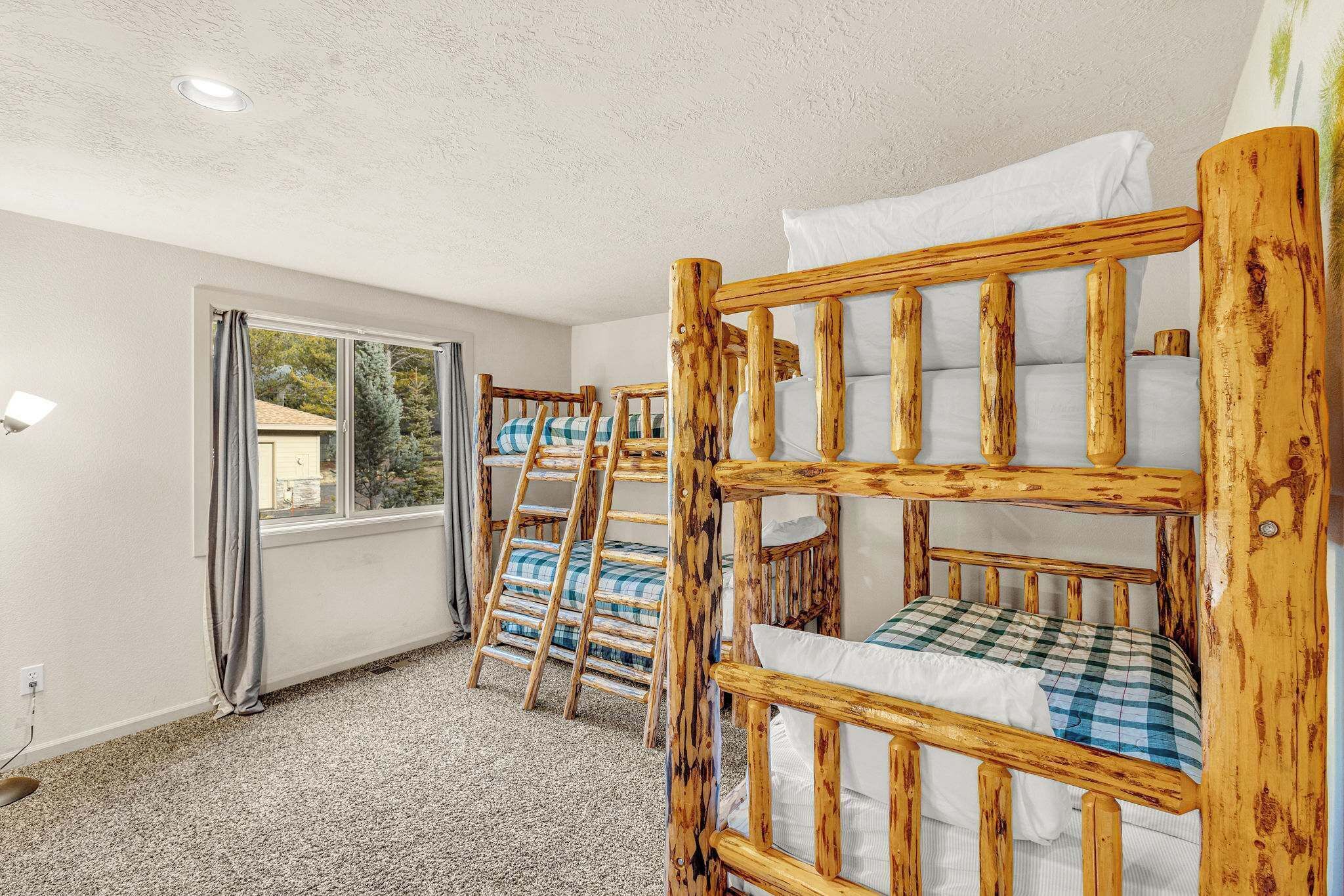 A room with bunk beds, a window with curtains, and a carpeted floor.
