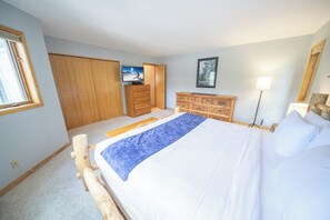 A bedroom with a large bed, wooden wardrobe, and a television on a dresser. - Keystone Winter Stay | Balcony & Mountain Views (Keystone)