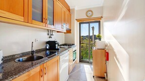 A kitchen with wooden cabinets, a granite countertop, a sink, a stove, and a dishwasher.