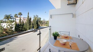 A balcony with a table, chairs, and a potted plant.