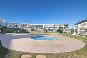Un espace piscine doté d’une piscine circulaire, d’un toit plat et d’un bâtiment comportant de nombreux balcons.