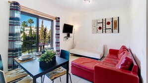 A modern living room with a dining area, a red sofa, and a TV mounted on the wall.