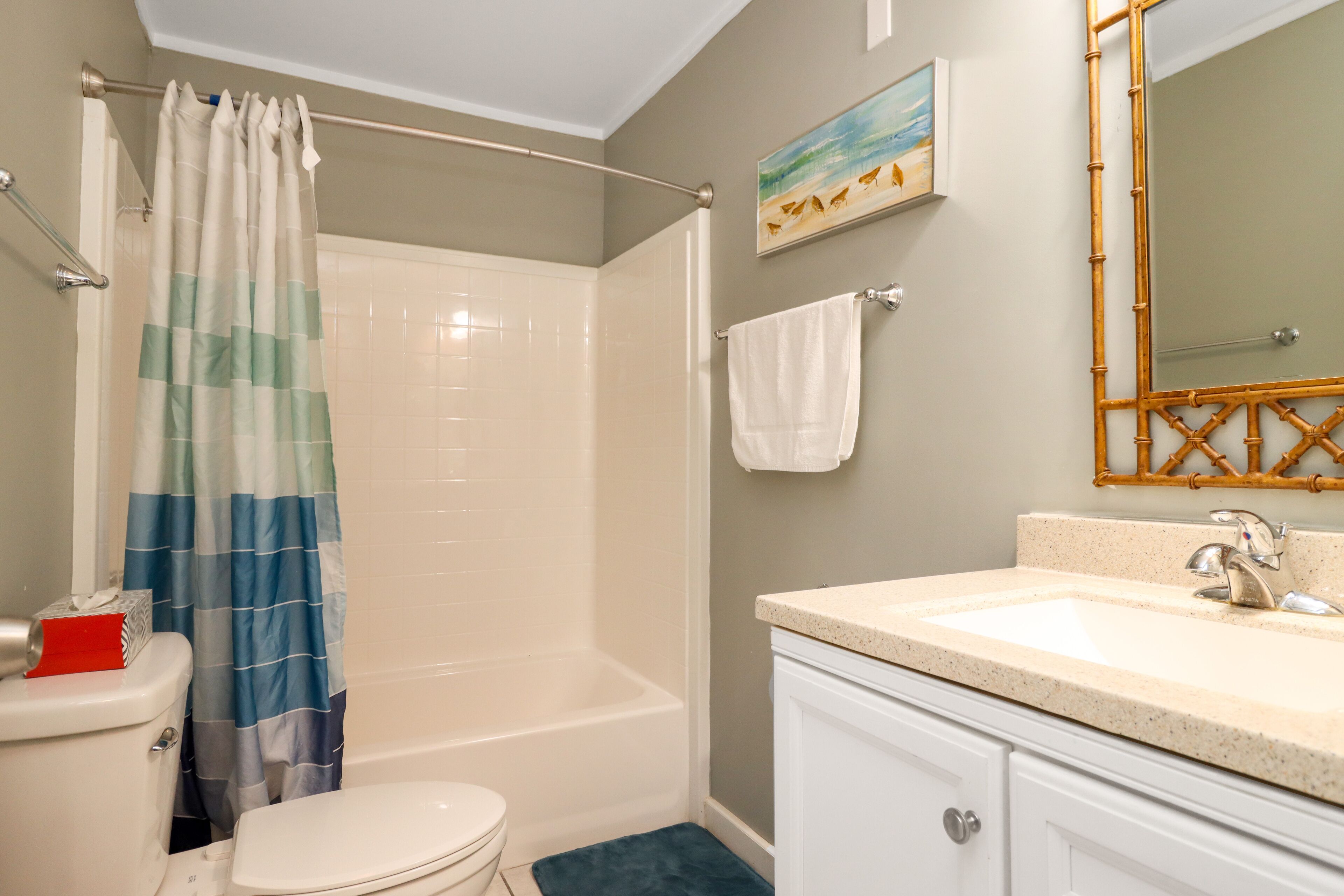 A bathroom with a shower, toilet, sink, and a mirror.