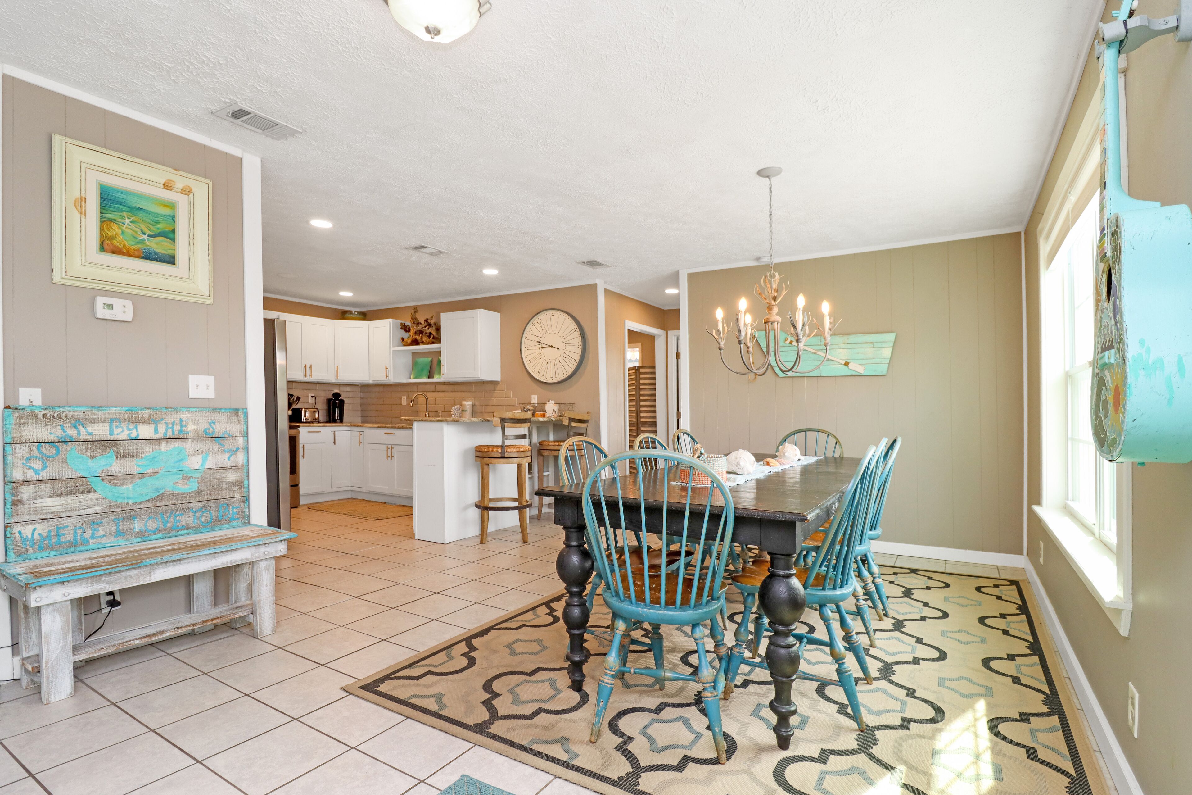A dining area with a wooden table and chairs, a bench, and a chandelier.