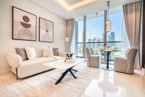 Relax in a spacious living room with a large sofa, armchair, and coffee table, surrounded by abstract art and city views.