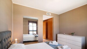 A bedroom with a bed, a bedside lamp, a dresser, and a mirror.