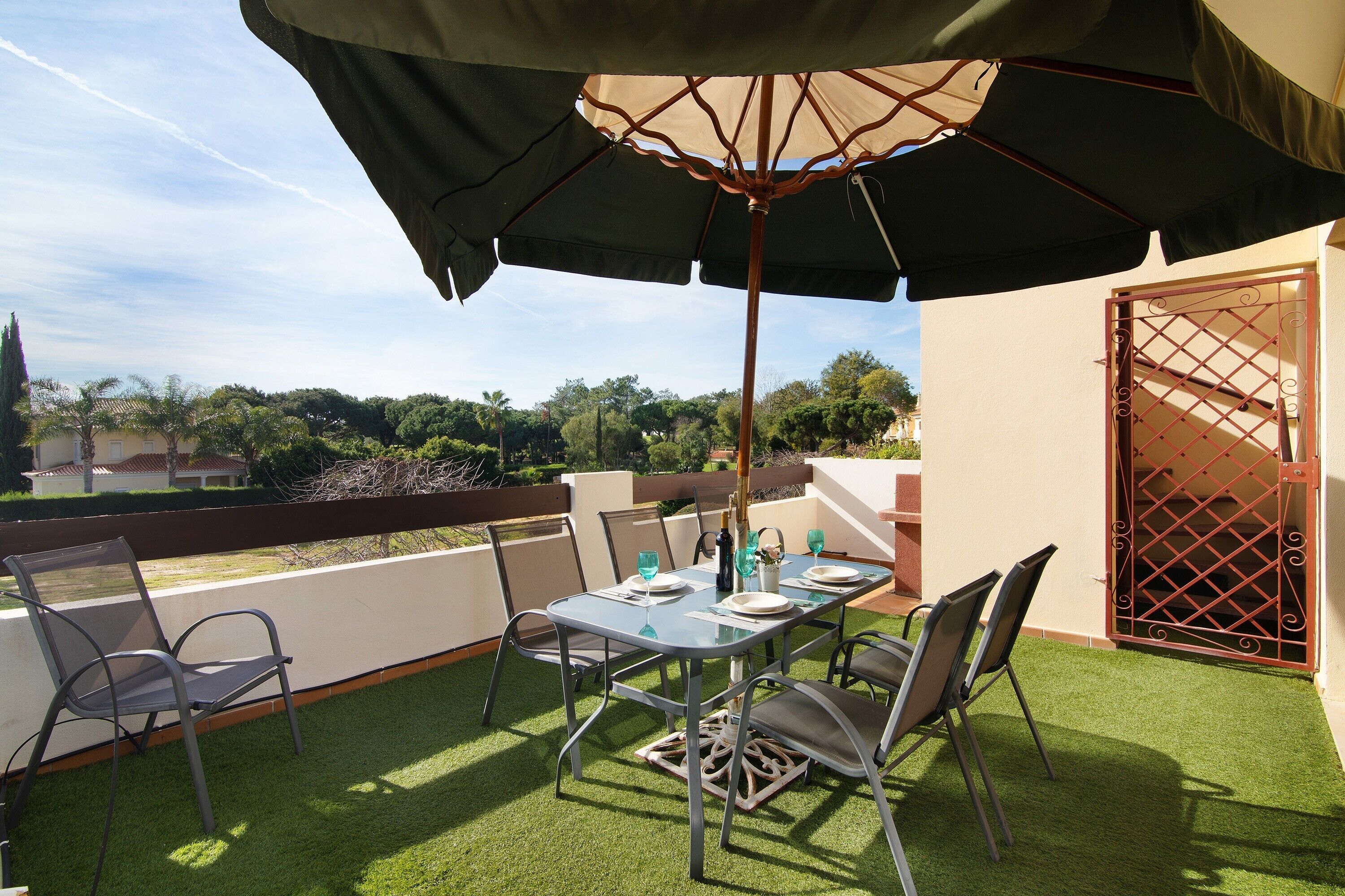 Een terras met een tafel, stoelen en een parasol.