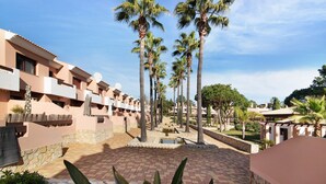 A resort with palm trees, a pool, and a brick courtyard.