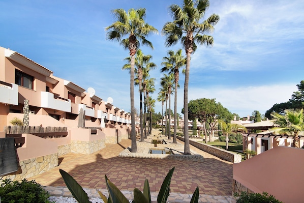 A resort with palm trees, a pool, and a brick courtyard.