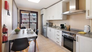 A compact kitchen with white cabinets, a stainless steel range, a microwave, and a gas stove.